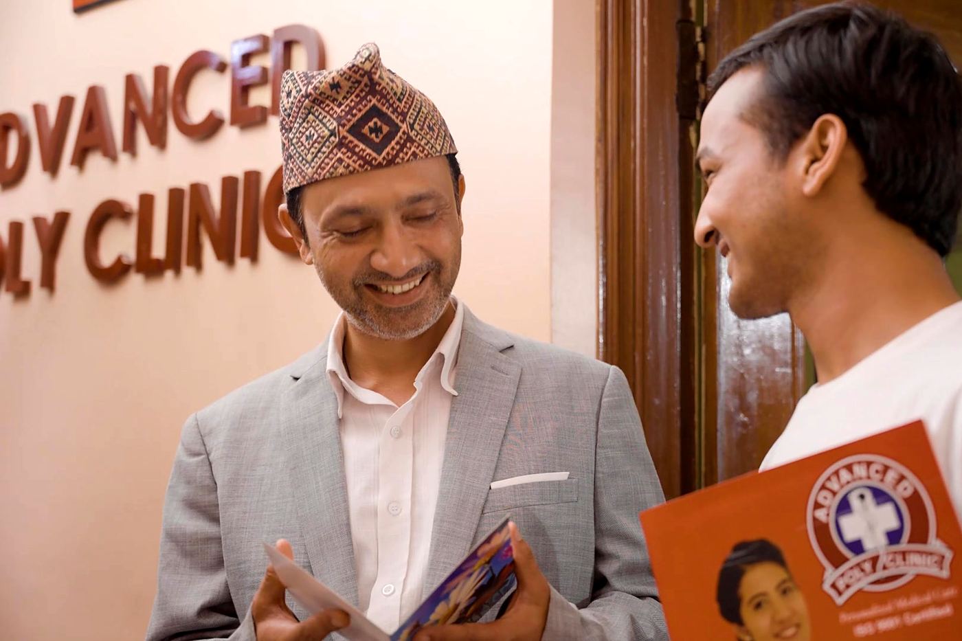 A father and son smiling over their APC health report at the clinic entrance